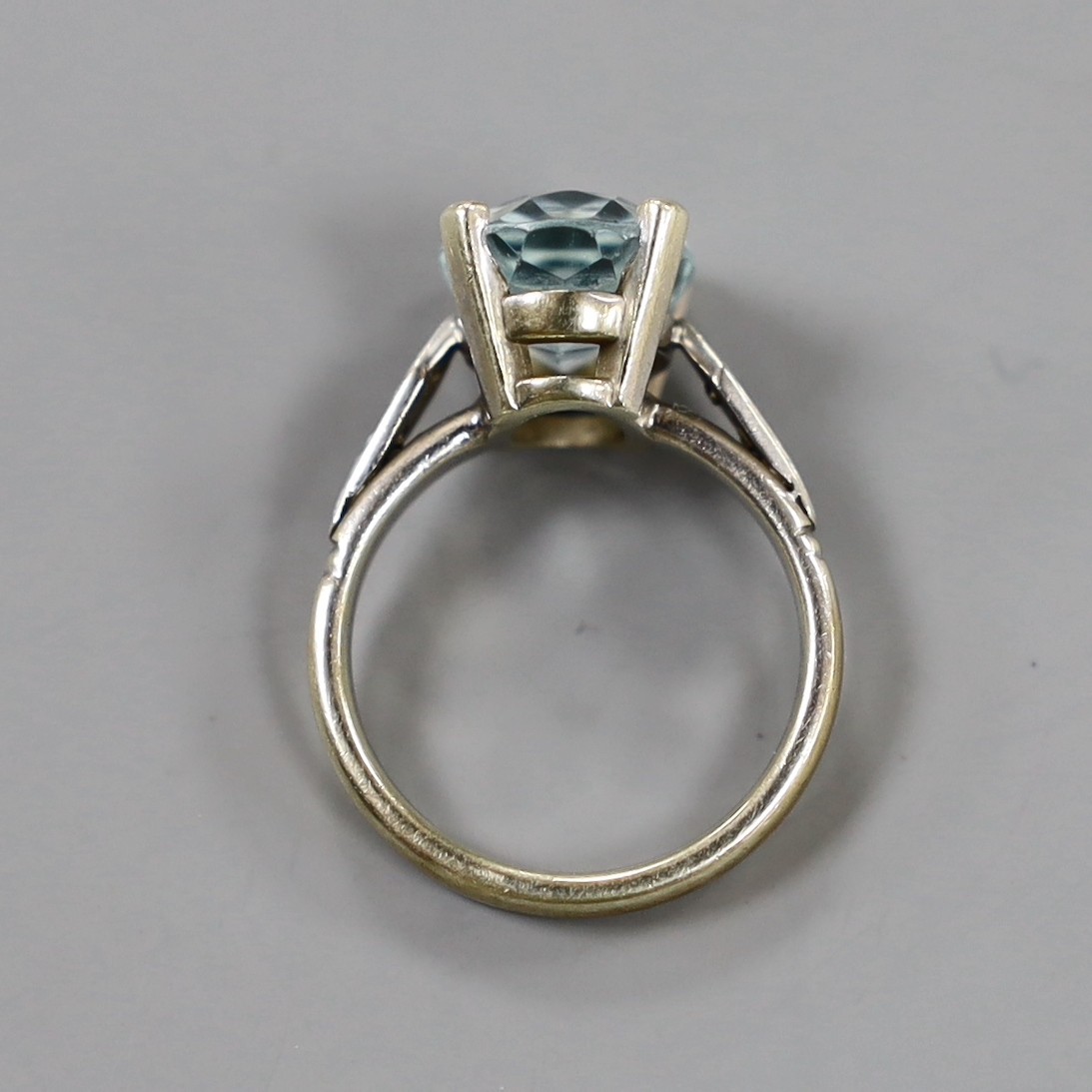 A modern yellow and white metal, oval cut aquamarine set dress ring, with diamond chip set shoulders, size N, gross weight 5.6 grams.